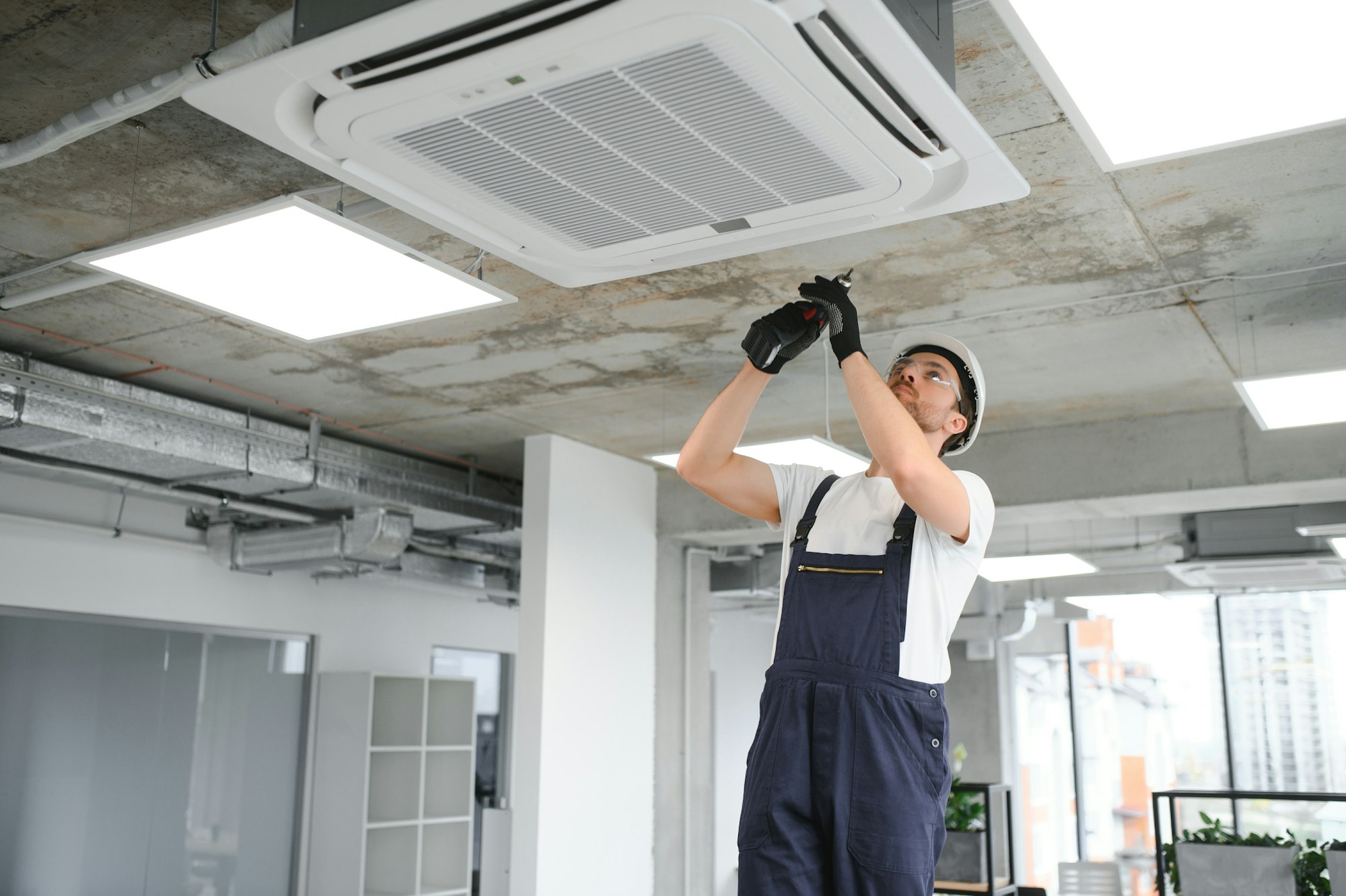 Electrician repairing air conditioner indoors